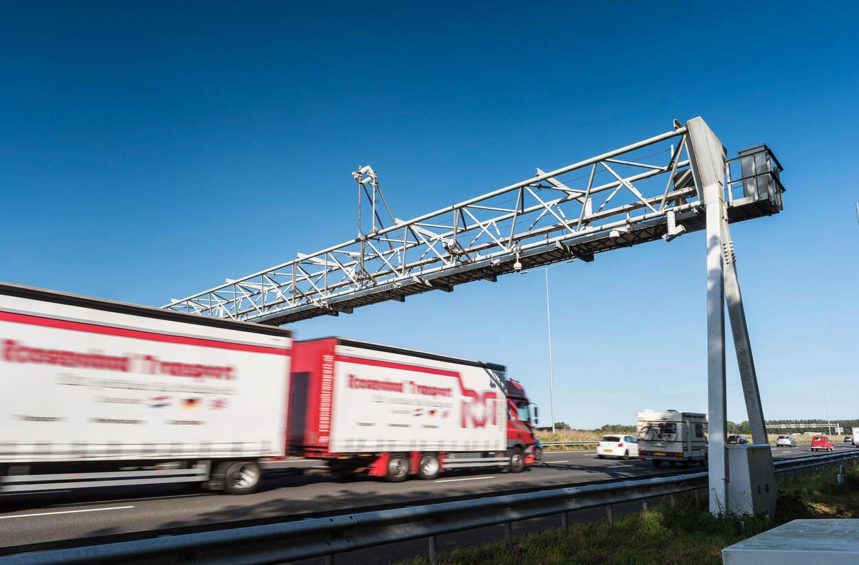 Vrachtwagen met aanhanger rijdt onder een cameraportaal door.